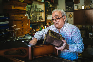 Watchmaker repairing antique clock mechanism in workshop