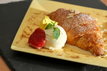 a plate of croissant with ice cream garnished with mint leaf and strawberry