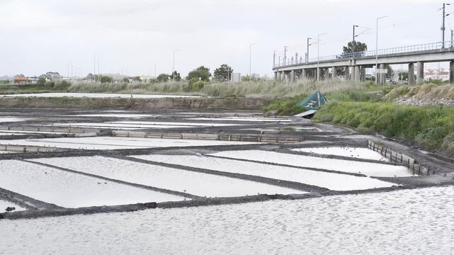 Close up view of a salt farm (salinas) in Ria de Aveiro, farm full of water waiting for the evaporation process. Windy day creating some movement on the water. Edges of the salinas full of small birds