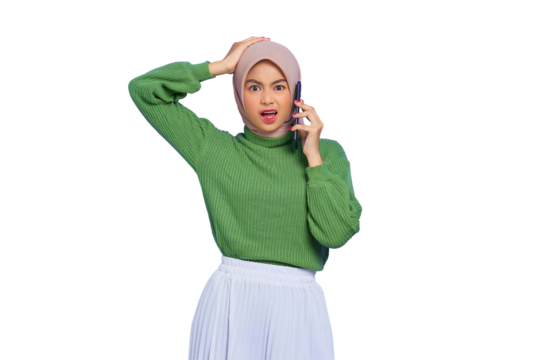 Shocked beautiful Asian woman in green sweater and hijab talking on mobile phone with open mouth isolated on transparent background