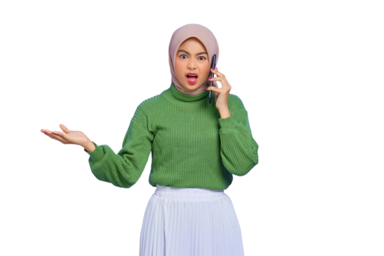 Shocked beautiful Asian woman in green sweater and hijab talking on mobile phone with open mouth isolated on transparent background