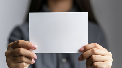 Hand holding blank paper card on neutral background