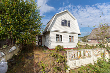 A small country house covered with plastic panels on a summer street.