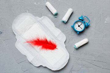 Ringing alarm clock with sanitary female tampons and menstrual sanitary pads. Medical concept of...