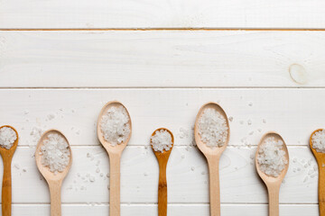 salt on many wooden spoon on wood background. Spoons with different salt