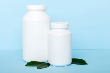 supplement pills with medicine bottle health care and medical top view. Vitamin tablets. Top view mockup bottle for pills and vitamins with green leaves, natural organic bio supplement, copy space