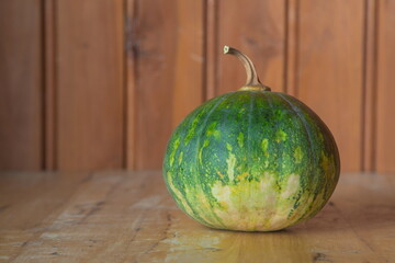 Green round pumpkin placed on a wooden background.