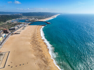 Coastal aerial showing Nazare's urban landscape, beach, and blue Atlantic waves