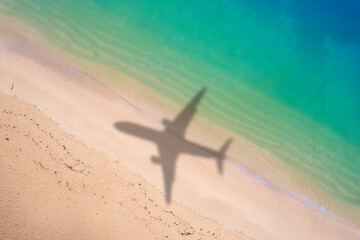 Aerial view of shadow passenger plane silhouette and sandy beach blue sea with waves at sea beach...