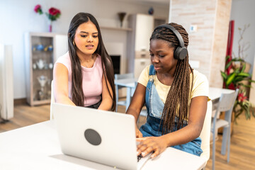 Teenage girls doing homework on laptop at home