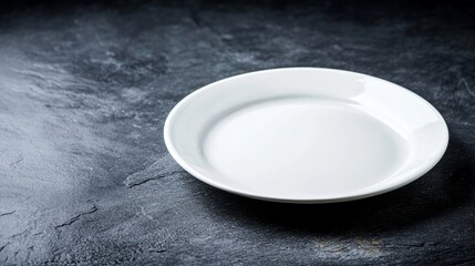 White plate sits on a black countertop. The plate is empty and the countertop is dark