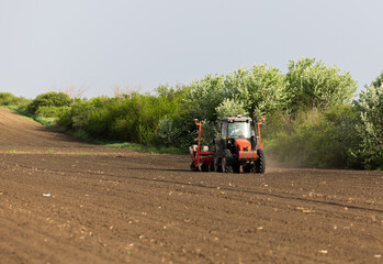 Farmer with tractor seeding in sunset