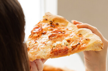 girl eating tasty delicious piece pizza with bacon, in cafe. woman holding with hand one...