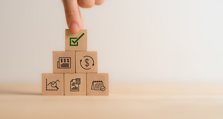 Financial approval concept. Stacked wooden blocks with financial icons, topped by a green checkmark...