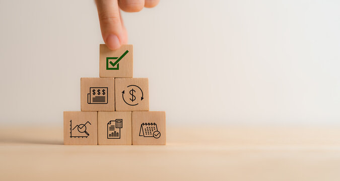 Financial approval concept. Stacked wooden blocks with financial icons, topped by a green checkmark block, indicating successful authorization and completion of financial procedures.