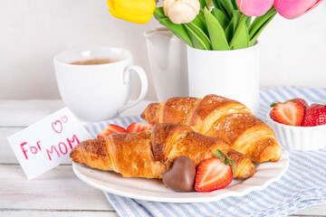 Mother’s Day breakfast background featuring croissant, strawberries, chocolates and coffee