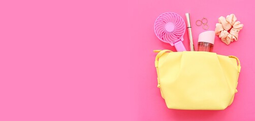 Cosmetic bag with portable electric fan and female accessories on pink background with space for...