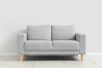 Stylish grey sofa near white wall