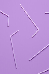 Lilac plastic straws on purple background
