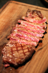 Succulent, perfectly grilled steak, sliced to reveal its tender, juicy interior and beautiful marbling, presented on a rustic wooden cutting board