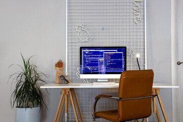 Programmer's workplace with computer monitor and glowing lamp in office