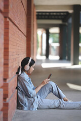 Asian college student wearing headphone listening music