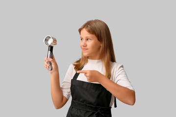 Portrait of teenage barista pointing at portafilter on grey background