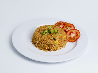 Indonesian fried rice served with tomato slices and scallions on a white plate, photographed from a side angle for appetizing presentation.