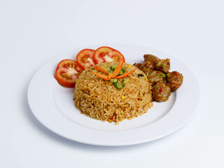 Indonesian fried rice with meatballs, tomato slices, and garnish on a white plate, shot from a side view for delicious presentation.