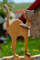Whimsical wooden cat silhouette graces a rustic garden fence in a quaint countryside village