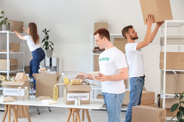 Obraz premium Male volunteer putting food into donation box in center