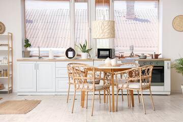 Interior of stylish kitchen with dining table, shelving unit, chairs and lamp