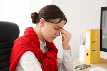 Young woman suffering from headache at workplace in office, closeup