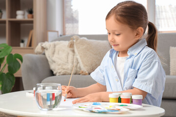 Cute little girl with glass of water painting at home