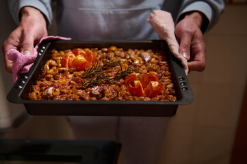 A close-up of a mouthwatering tray of baked beans just out of the oven, garnished with fresh...