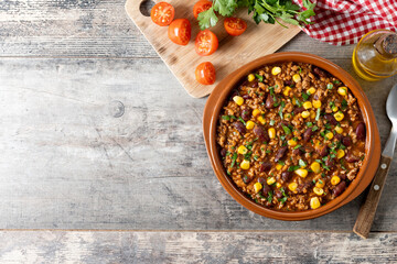 Traditional Mexican Chili con carne. Minced meat and vegetables stew in tomato sauce on wooden table