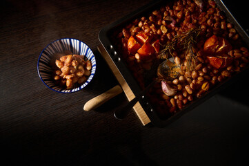 Homemade baked beans paired with fresh tomatoes and aromatic herbs served in a cozy tabletop...