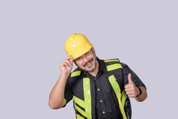 Smiling construction site worker tips his hard hat and gives a thumbs up, showing friendliness, approval, and professional confidence.