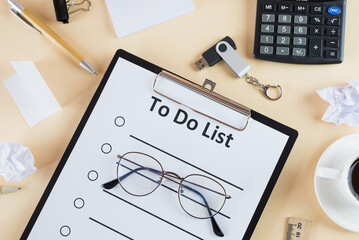 to do list on clipboard with office supplies, isolated on beige background
