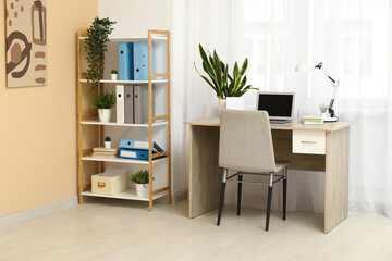 Interior of stylish office with shelf unit, folders and workplace
