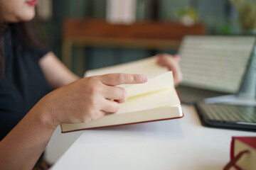 Asian woman reading a book in living room