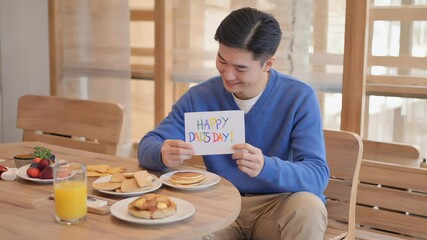 A man celebrates Fathers Day by sitting at a table with a plate of food, symbolizing a moment of appreciation and gratitude.