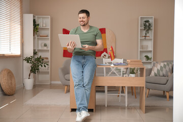 Handsome man with laptop learning Spanish online at home
