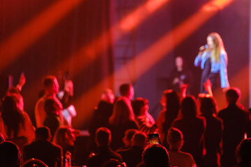 Crowd watching a singer perform on stage with vivid light effects and dynamic ambiance.