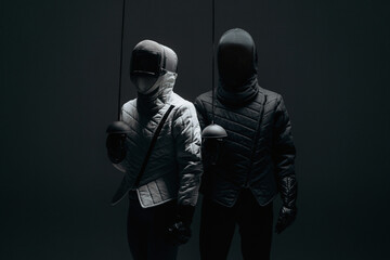 Two Fencers in Protective Gear Standing in a Dark Environment..