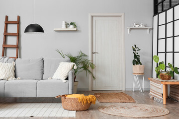 Interior of living room with wooden ladder, sofa and door