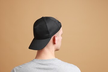 Man in stylish baseball cap on beige background, back view. Mockup for design