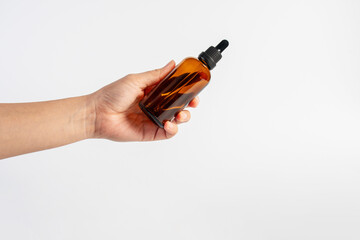Cosmetic bottles made of dark amber glass and hand on white background