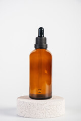 Cosmetic bottles made of dark amber glass with stylish props on white background
