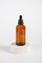 Cosmetic bottles made of dark amber glass with stylish props on white background